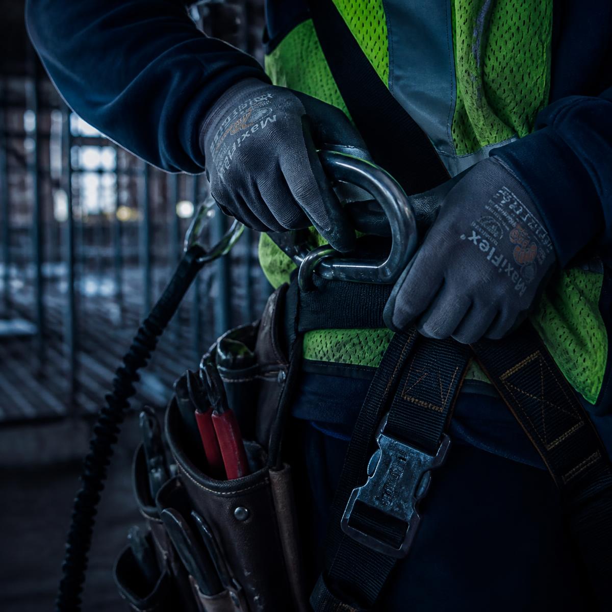 Electrician securing a fall-protection harness on an industrial jobsite